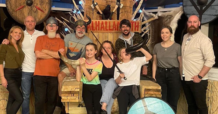family group posing for photo at Valhalla North Axe Throwing on Viking throne